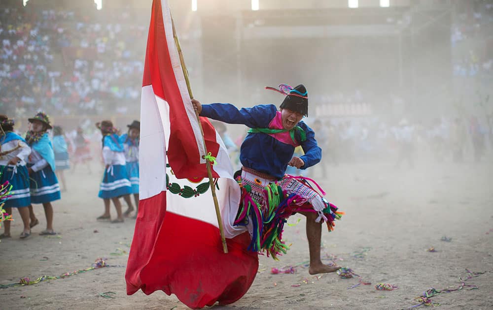 a man from the La Mar district of Ayacucho, sings in Quechua, holding a Peruvian national flag as he performs in the Vencedores de Ayacucho dance festival, in the Acho bullring in Lima, Peru. 