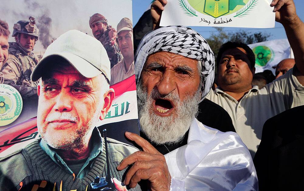 An Iraqi Shiite protester holds a poster showing Iraqi militia leader Hadi al-Amiri of the Badr forces during a protest against the military intervention in Yemen, in Baghdad, Iraq.