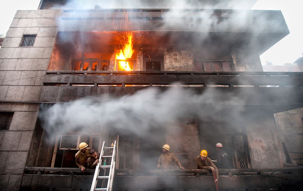 firefighters work to extinguish a fire as smoke billows from a building in Gandhinagar market in New Delhi.