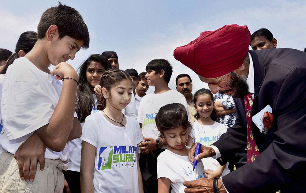 Legendary athlete Milkha Singh gives autographs on the T-shirt of a child during a programme to start sports education among school children in India.