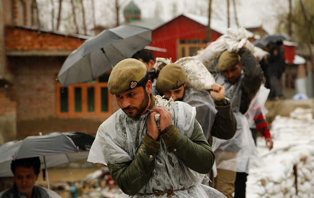 Jammu and Kashmir policemen carry sand bags to repair a breach in an embankment in a flooded area of Srinagar, India.