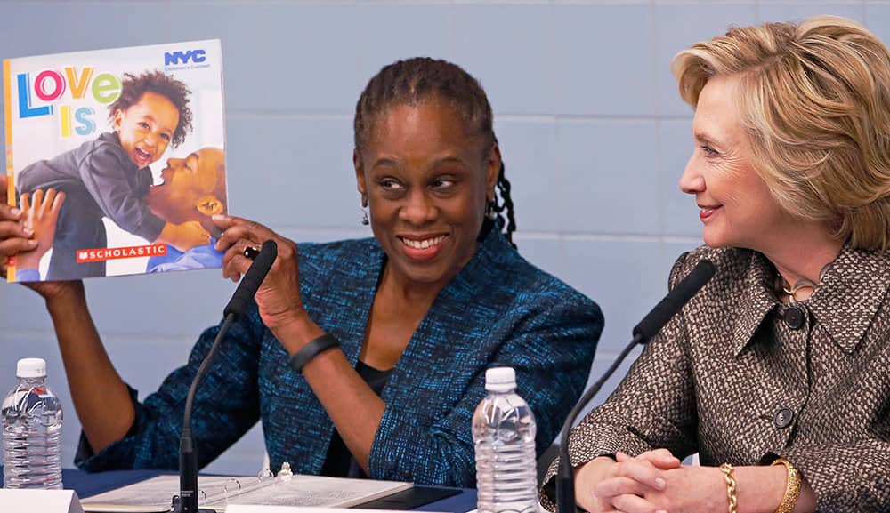 Hillary Rodham Clinton watches as New York City's First Lady Chirlane McCray holds up a booklet that is to be distributed to parents to encourage them to talk to their very young children during a visit to First StepNYC, an early childhood development center in the Brooklyn borough of New York.
