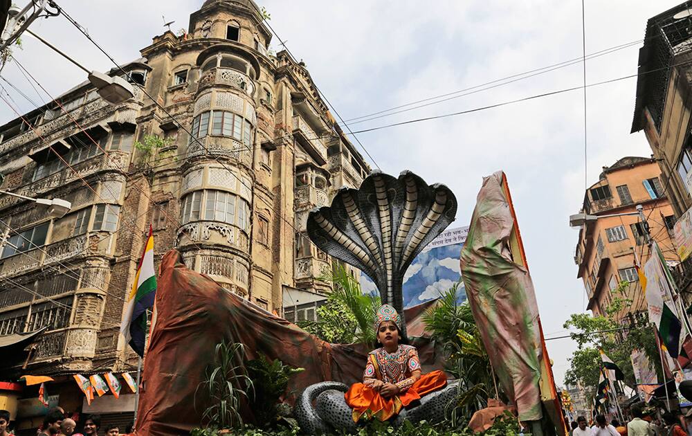 A child dressed as Hindu god Krishna sits in a tableau as it rolls past an old building during a procession marking Jain festival, Mahavir Jayanti in Kolkata.