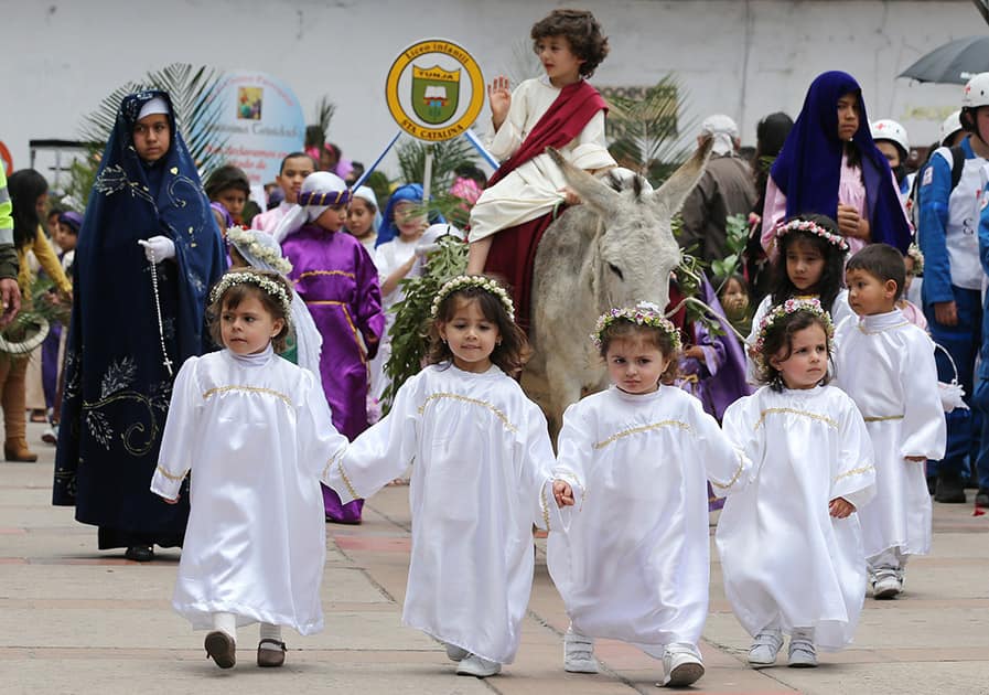 Children dressed as angels lead a boy portraying Jesus Christ and his triumphant return to Jerusalem, in the Children's Holy Thursday Procession, in Tunja, Colombia.