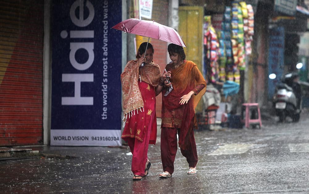 Women walk under an umbrella during a spell of unseasonal rain in Jammu.