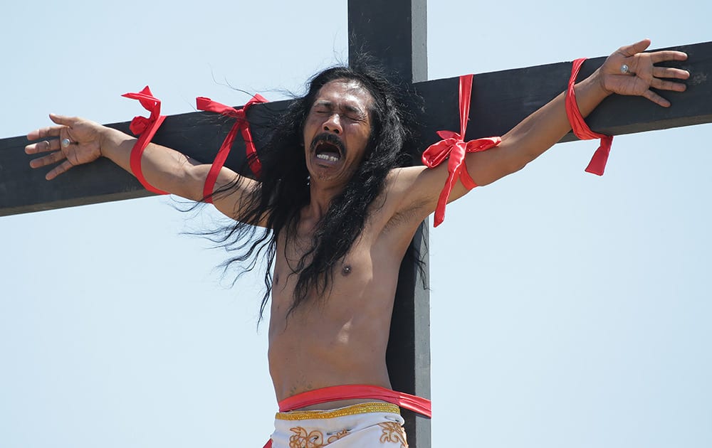 A Filipino penitent grimaces as he is nailed to the cross during Good Friday rituals at Cutud, Pampanga province, northern Philippines. 