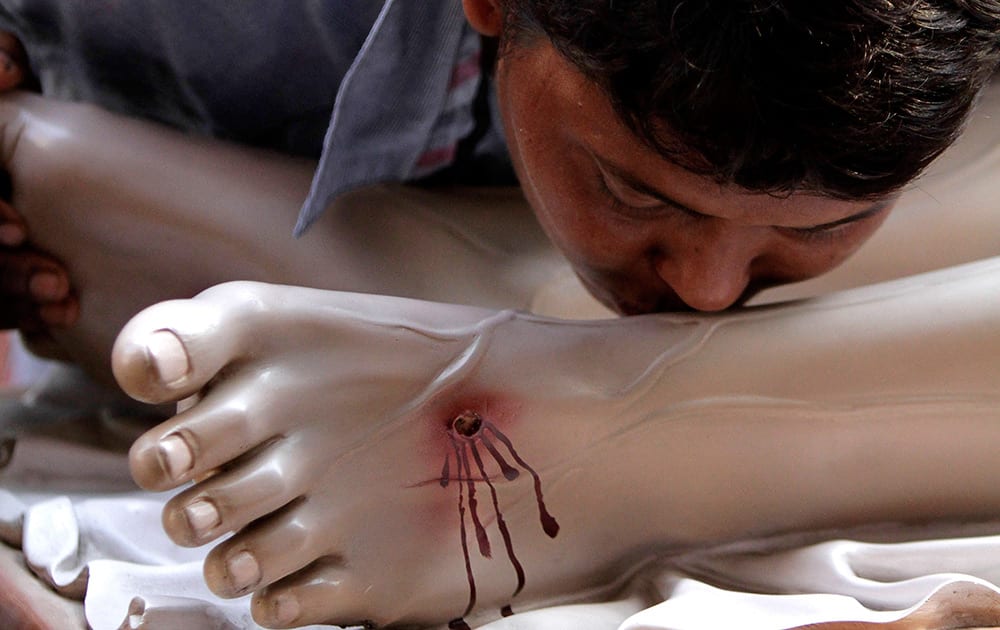 An Indian Christian kisses the feet of a clay model of Jesus Christ on Good Friday, in Kolkata.