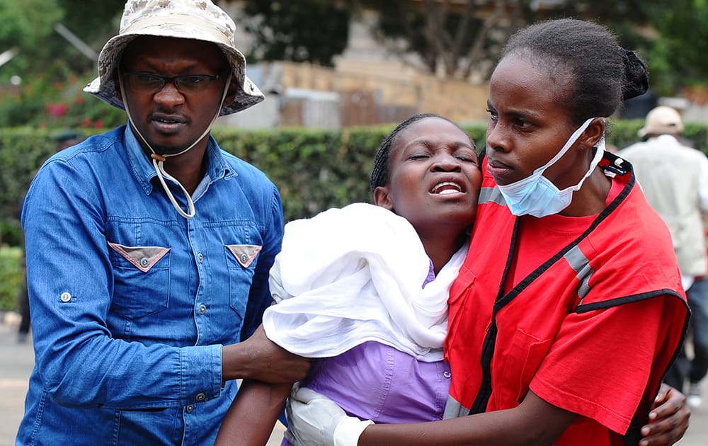 Kenya Red Cross staff help a woman after she viewed the body of a relative killed in Thursday's attack on a university, at Chiromo funeral home, Nairobi, Kenya.