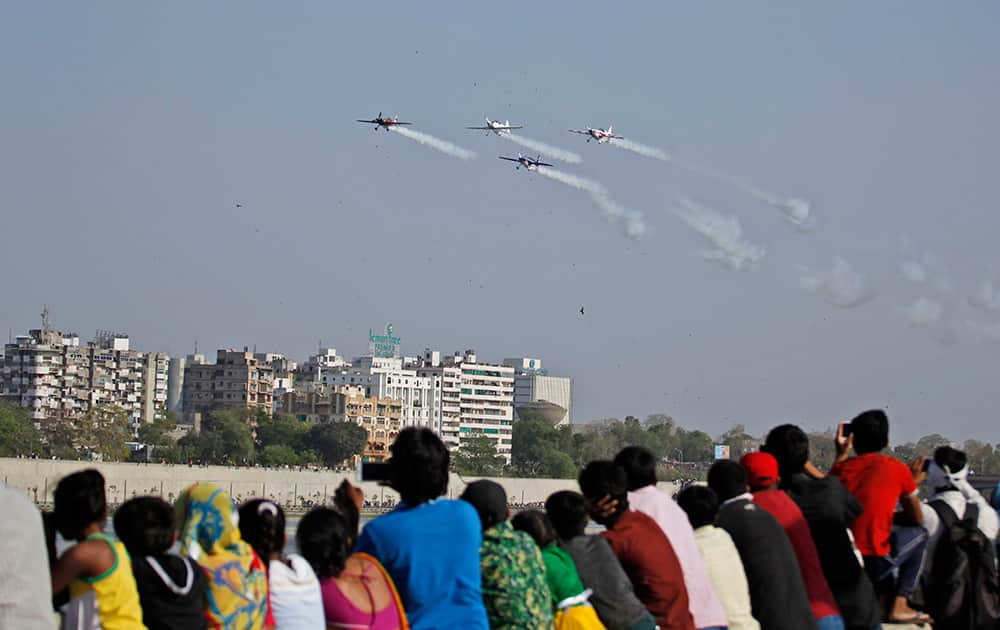 People watch as aircrafts of the British aerobatics team Global Stars perform during the third day of an air show in Ahmadabad.