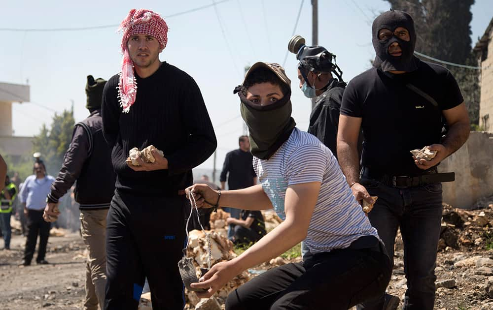 Palestinian protestors prepare to throw stones at Israeli troops during clashes following a protest against the nearby Jewish settlement of Kdumim in the West Bank village of Kufr Qaddum.