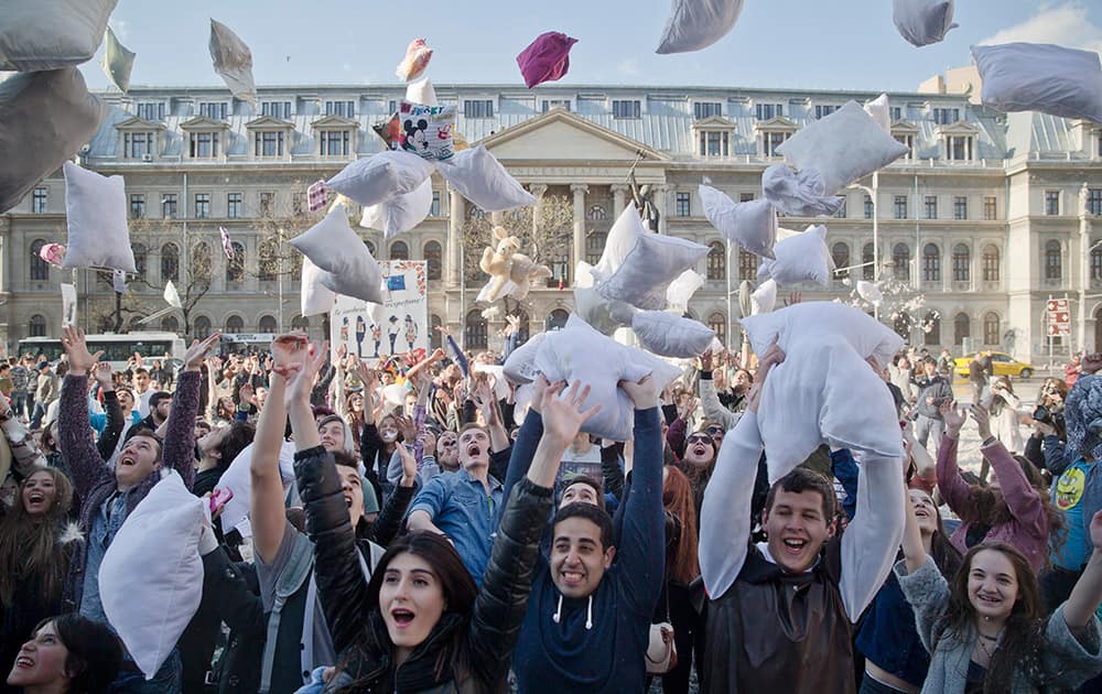 Youngsters throw pillows in the air for a photograph after taking part in a pillow fight downtown Bucharest, Romania.