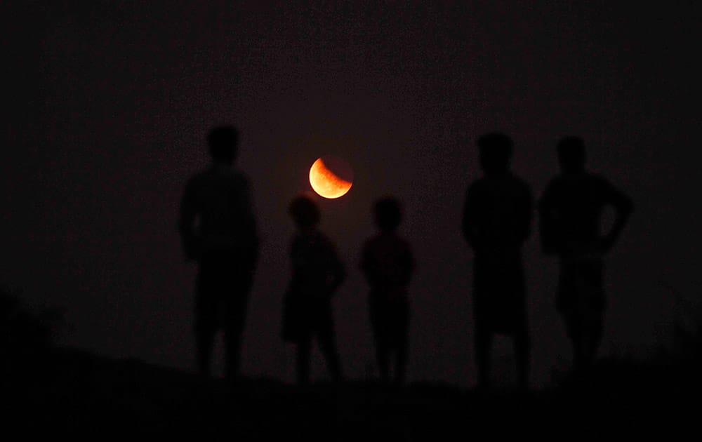 Indians watch a lunar eclipse from the banks of River Kuakhai on the outskirts of Bhubaneswar.
