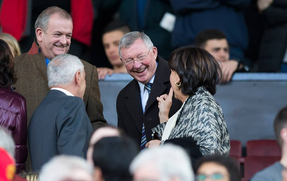 Manchester United's former manager Alex Ferguson, centre, laughs as he takes his seat before the English Premier League soccer match between Manchester United and Aston Villa at Old Trafford Stadium, Manchester, England.