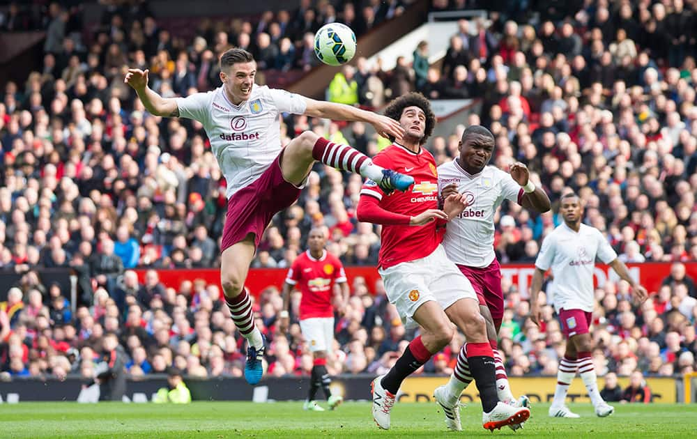 Aston Villa's Ciaran Clark, left, clears the ball away from Manchester United's Marouane Fellaini as Jores Okore looks on during the English Premier League soccer match between Manchester United and Aston Villa at Old Trafford Stadium, Manchester, England.