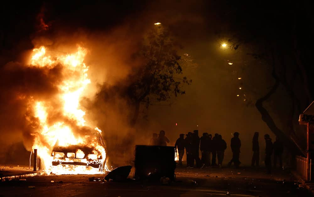 Rioting youths stands next to a car on fire during clashes after a demonstration by about 700 anarchists seeking the abolition of a maximum security prison, in central Athens.