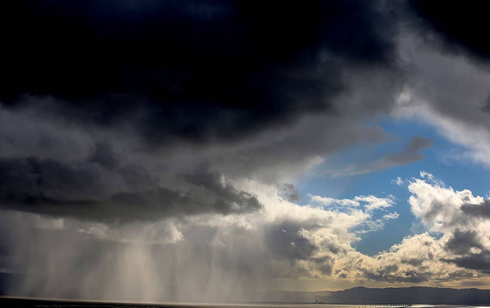 Storm clouds and rain move across the San Francisco Bay, in Hayward, Calif.