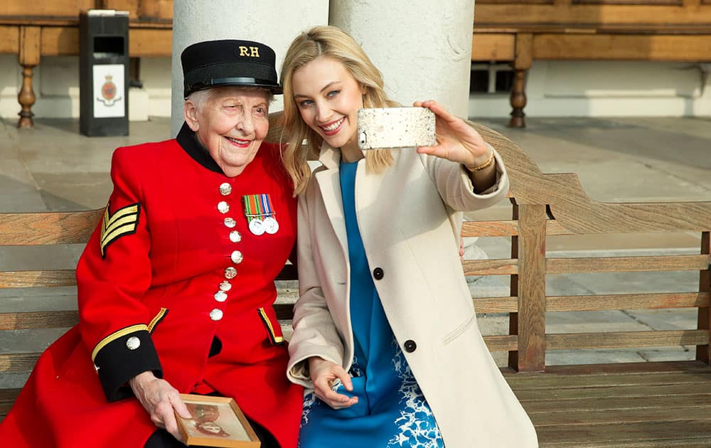 Canadian actress Sarah Gadon, who will portray Princess Elizabeth in the feature film 'A Royal Night Out' - the future British Queen Elizabeth II, takes a picture with her smart phone with Chelsea Pensioner Dorothy Hughes at a photocall ahead of the release of the film in London.