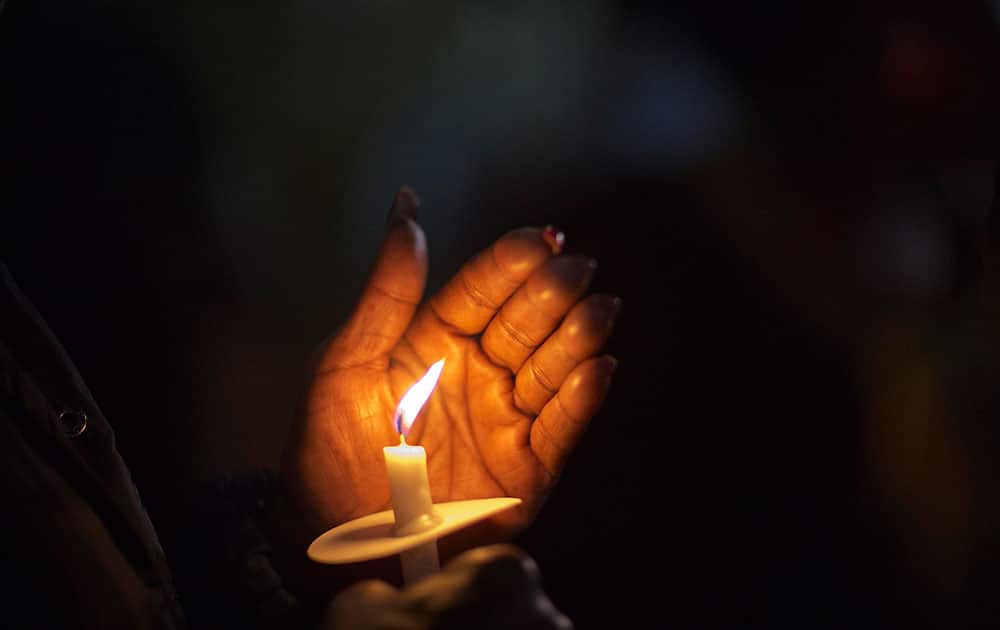 A mourner holds a candle during a vigil outside city hall protesting the shooting death of Walter Scott, in North Charleston, S.C. Scott was killed by a North Charleston police office after a traffic stop on Saturday. The officer, Michael Thomas Slager, has been charged with murder.