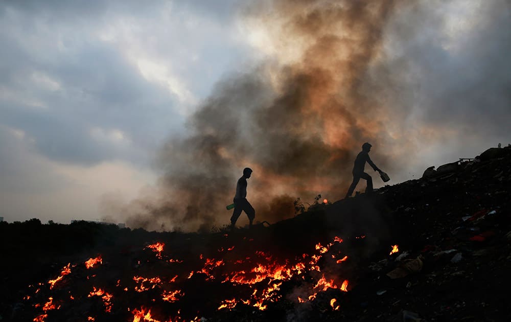 Impoverished Indians walk next to burning trash after relieving themselves in the open at Dharavi, one of the world’s largest slums, in Mumbai.