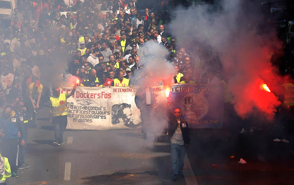 Dockers of Marseille-Fos harbour burn flares during a demonstration with employees, teachers and workers against austerity, in Marseille, southern France.