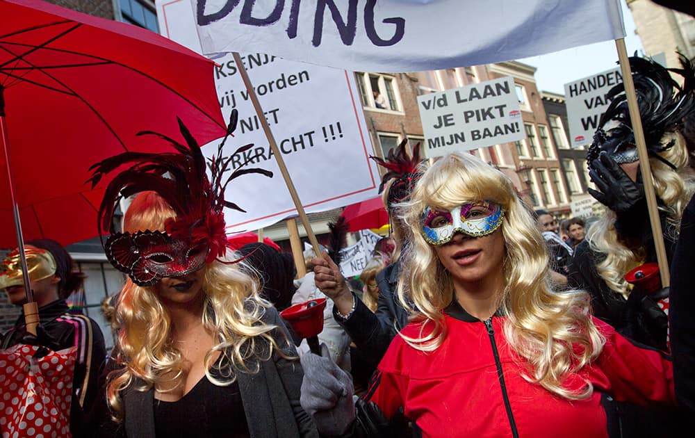 Masked women hold banners as prostitutes and sympathizers take to the streets to protest plans to clean up the city's famed red light district by shuttering windows where scantily-clad sex workers pose to attract clients, Amsterdam, Netherlands.