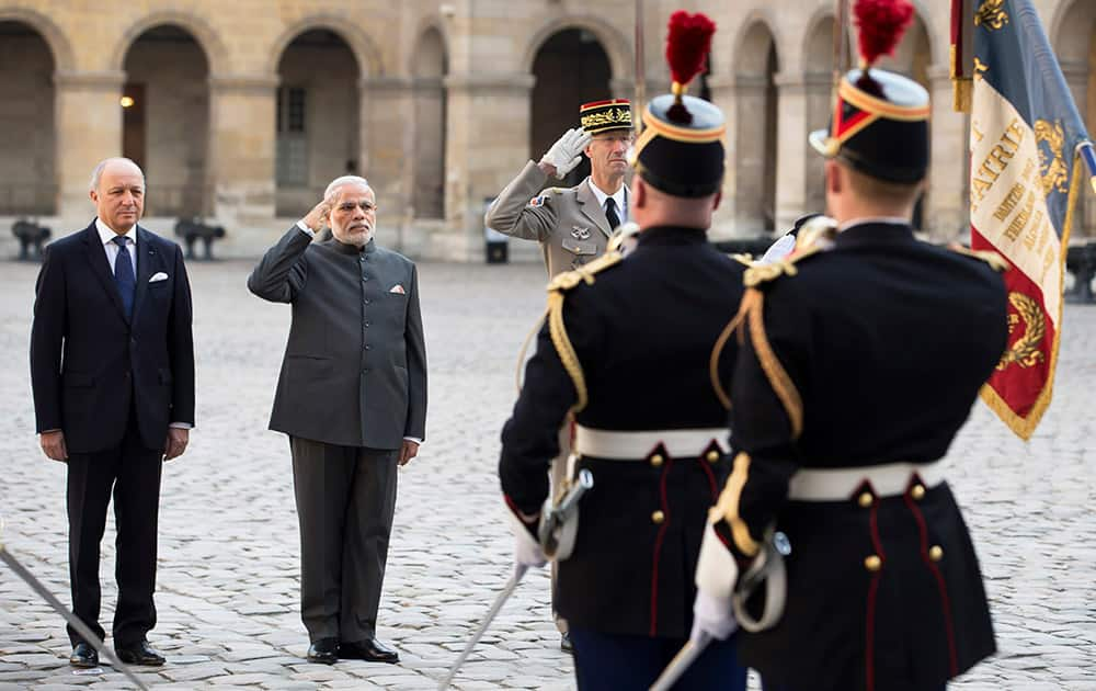 Prime Minister Narendra Modi, accompanied by French Foreign Minister Laurent Fabius, salutes the French flag during a welcoming ceremony in the courtyard of the Hotel des Invalides in Paris.