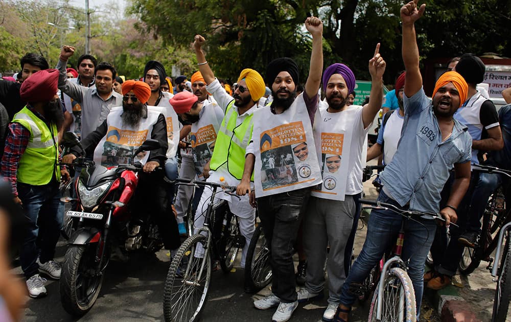 Sikhs shout slogans as they participate in a cycle rally protesting the 1984 anti-Sikh riots in New Delhi.