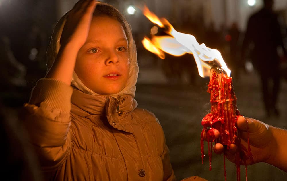 A girl blesses herself with the Holy Fire which was delivered to the Ukrainian capital from the Church of the Holy Sepulcher in Jerusalem's Old City, traditionally believed to be the burial place of Jesus Christ, after the ceremony of the Holy Fire on the Easter service in the Monastery of Caves in Kiev, Ukraine.