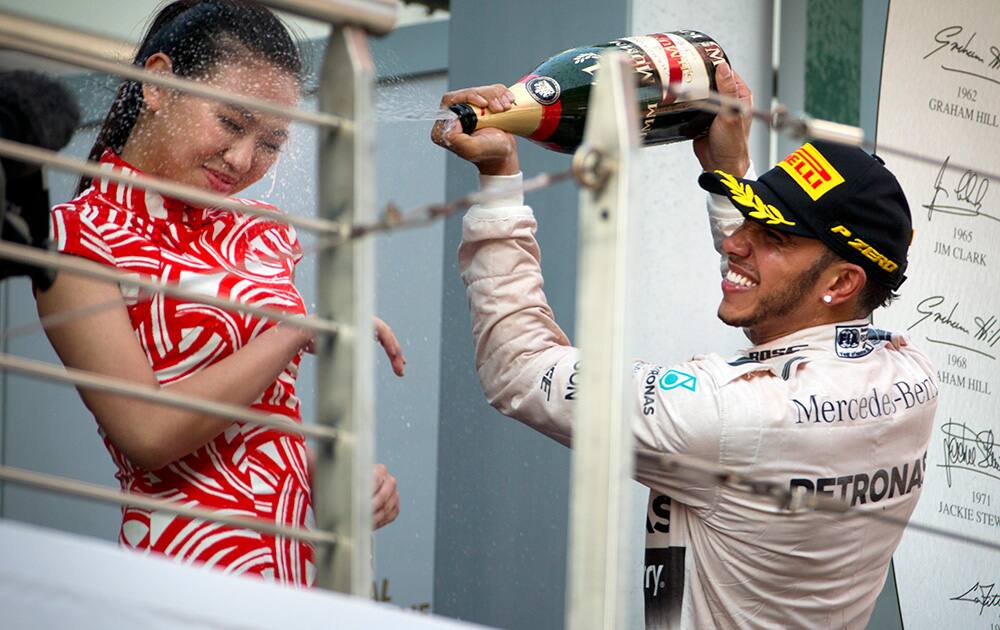 Mercedes driver Lewis Hamilton of Britain sprays champagne on a track attendant on the podium after winning the Chinese Formula One Grand Prix at Shanghai International Circuit.