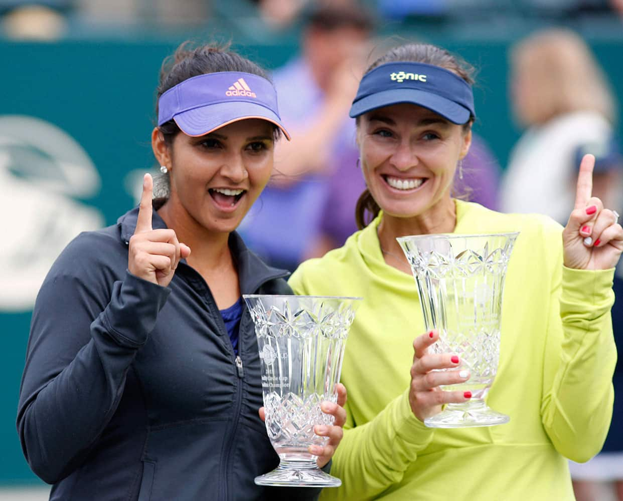 Sania Mirza of India, and her teammate, Martina Hingis of Switzerland, hold their trophies after defeating Alla Kudryavtseva and Anastasia Pavlyuchenkova during a doubles final match at the Family Circle Cup tennis tournament.