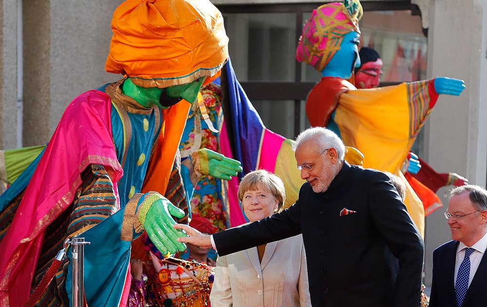 German Chancellor Angela Merkelwelcomes India's Prime Minister Narendra Modi as a traditional Indian music group performs at the opening of the industrial fair in Hanover, Germany.