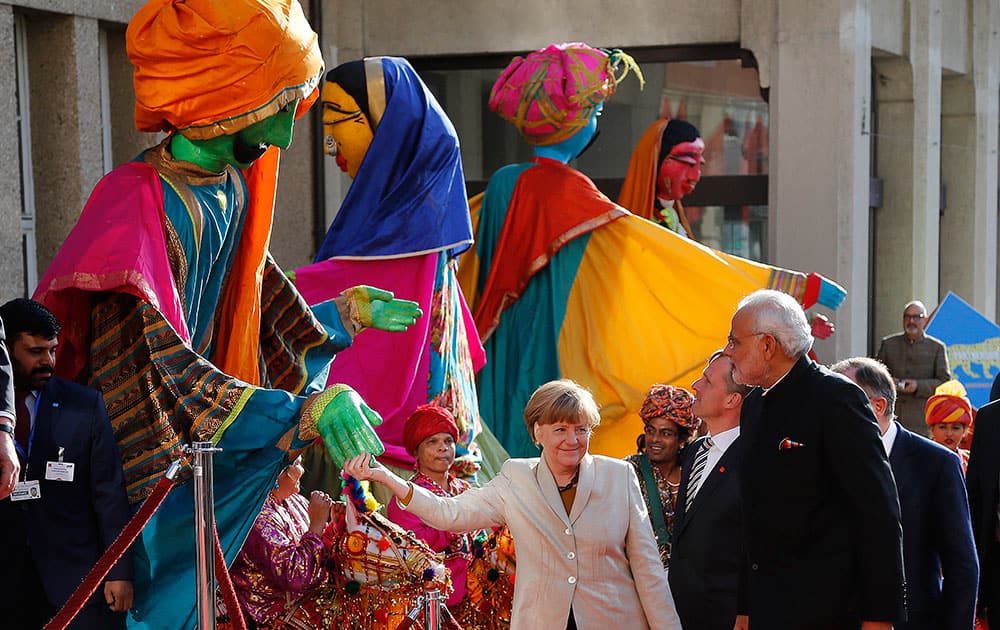 German Chancellor Angela Merkel welcomes India's Prime Minister Narendra Modi as a traditional Indian music group performs at the opening of the industrial fair in Hanover, Germany.