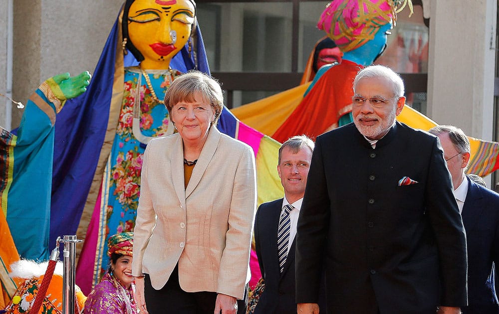 German Chancellor Angela Merkel, welcomes Indias Prime Minister Narendra Modi, as a traditional Indian music group performs at the opening of the industrial fair in Hanover, Germany.