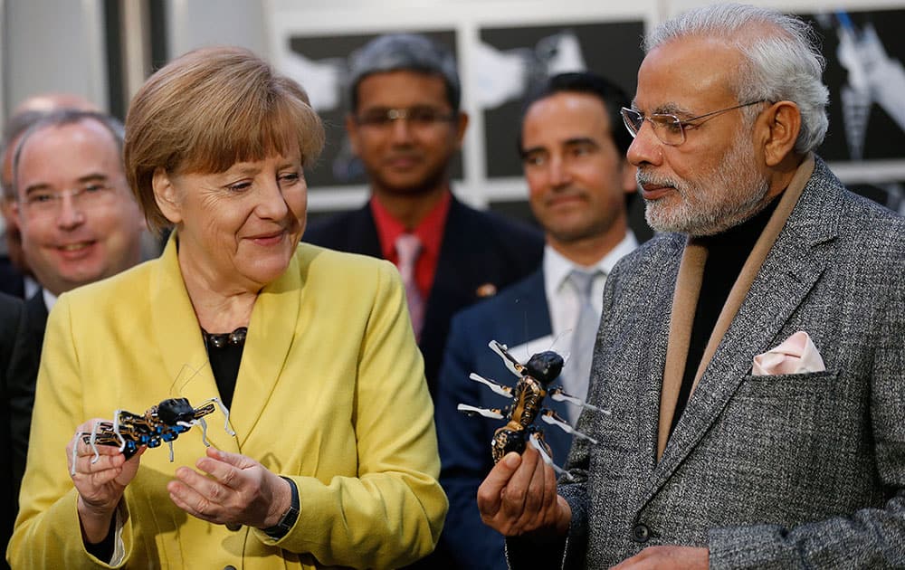 German Chancellor Angela Merkel and India's Prime Minister Narendra Modi hold bionic ants at the Festo company's booth during the opening of the industrial fair in Hanover, Germany.