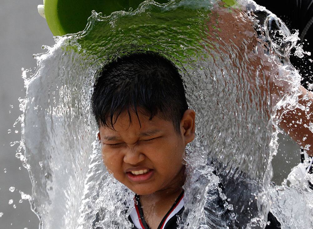 A boy reacts as a bucket of water is thrown on his head during the Songkran water festival to celebrate Thai New Year in Bangkok, Thailand.