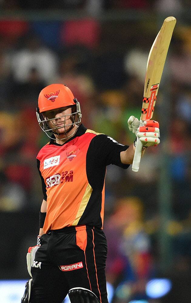 Sunrisers Hyderabad David Warner raises his bat after completing his half century against Royal Challengers Bangalore during IPL 8 match at Chinnaswamy Stadium in Bengaluru.