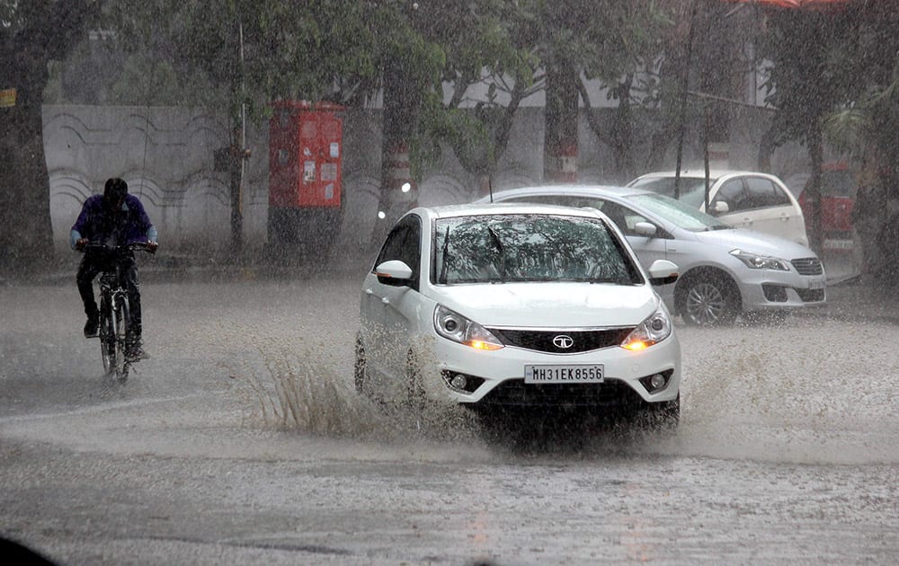 Vehicles move on a waterlogged street during heavy rains in Nagpur.