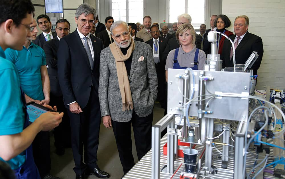 Prime Minister of India, Narendra Modi and Siemens CEO Joe Kaeser, look at a 'coffee machine' build by trainees during a visit of the Siemens company in Berlin, Germany.