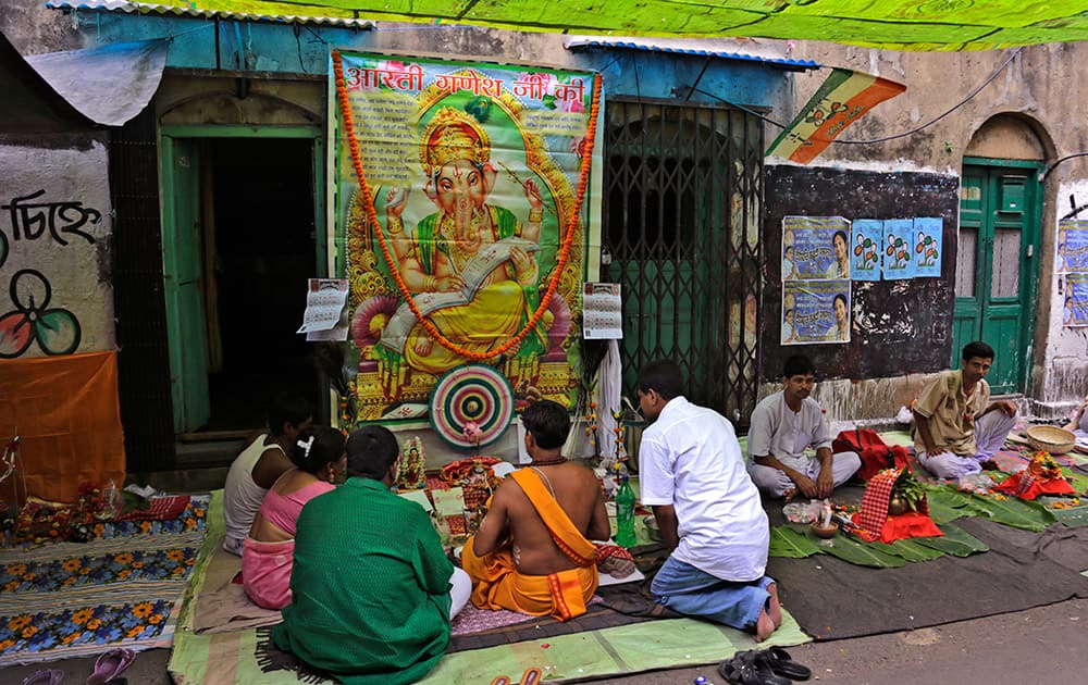 Devotees sit in front of a picture of Lord Ganesha as they surround a priest to perform rituals to mark Bengali New Year in Kolkata.