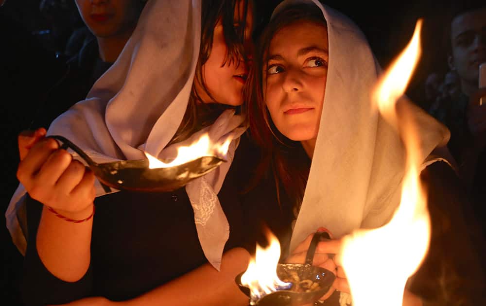 A Yazidi woman whispers into the ear of her friend as both hold small fires to make a wish for the Yazidi new year, at the holy shrine of Lalish, 57 kilometers (35 miles) north of the militant-held Mosul, Iraq.