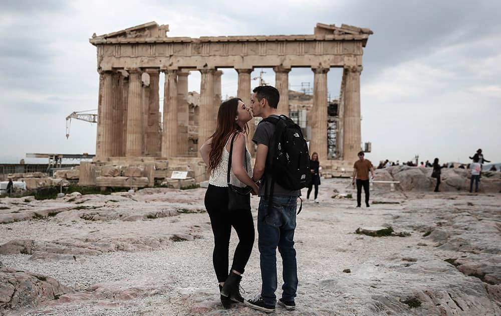 US visitors Zach Branch,19, right, and Madison Franklin, 18, both from California, kiss in front of the Parthenon during their visit at the Acropolis hill in Athens.