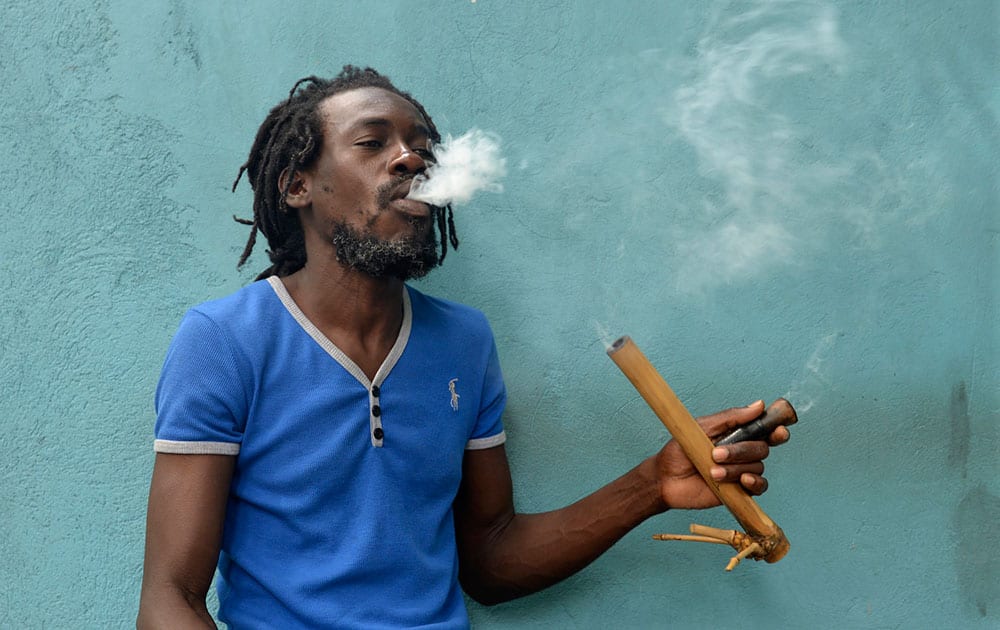 A Jamaican Rastafarian known as Nature smokes marijuana outside the Trench Town Culture Yard Museum in downtown Kingston, Jamaica.