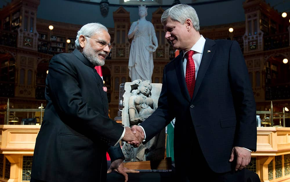 Canadian Prime Minister Stephen Harper shakes hands with Prime Minister Narendra Modi as Harper returns a sculpture of a woman known as 'parrot lady' at the Parliamentary Library on Parliament Hill in Ottawa.