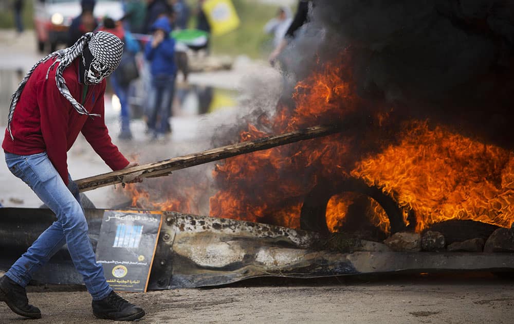 A Palestinian protesters burn tyres during clashes with Israeli troops following a protest marking Palestinian 'Prisoners' Day', outside Ofer military prison near the West Bank city of Ramallah.