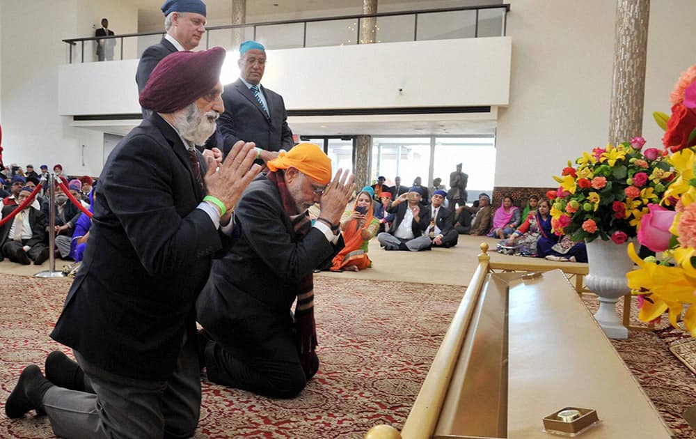 Prime Minister Narendra Modi kneels in reverence during his visit to Gurudwara Khalsa Diwan as his Canadian counterpart looks on in Vancouver.