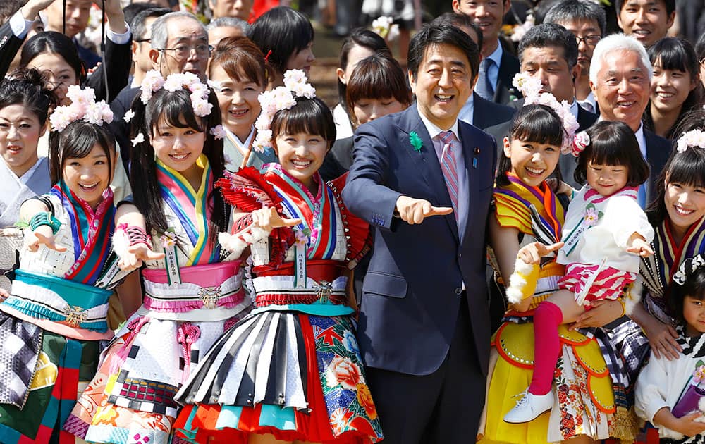 Japan's Prime Minister Shinzo Abe strikes a pose with members of Japan's girl pop unit 'Momoiro Clover Z' during the annual cherry blossoms viewing party hosted by Abe at Shinjuku Gyoen National Garden park in Tokyo.