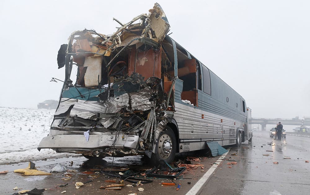 Investigators look over a tour bus involved in an accident with a tractor trailer, in Aurora, Colo. At least 11 people were injured, two of them critically, in the four-vehicle wreck that shut down Interstate 70 for several hours during a spring storm packing heavy rains and fog.