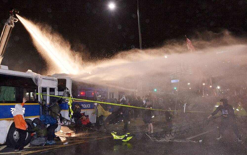 riot police officers spray water to disperse protesters after a rally to commemorate the first anniversary of the Sewol ferry sinking in Seoul, South Korea. 