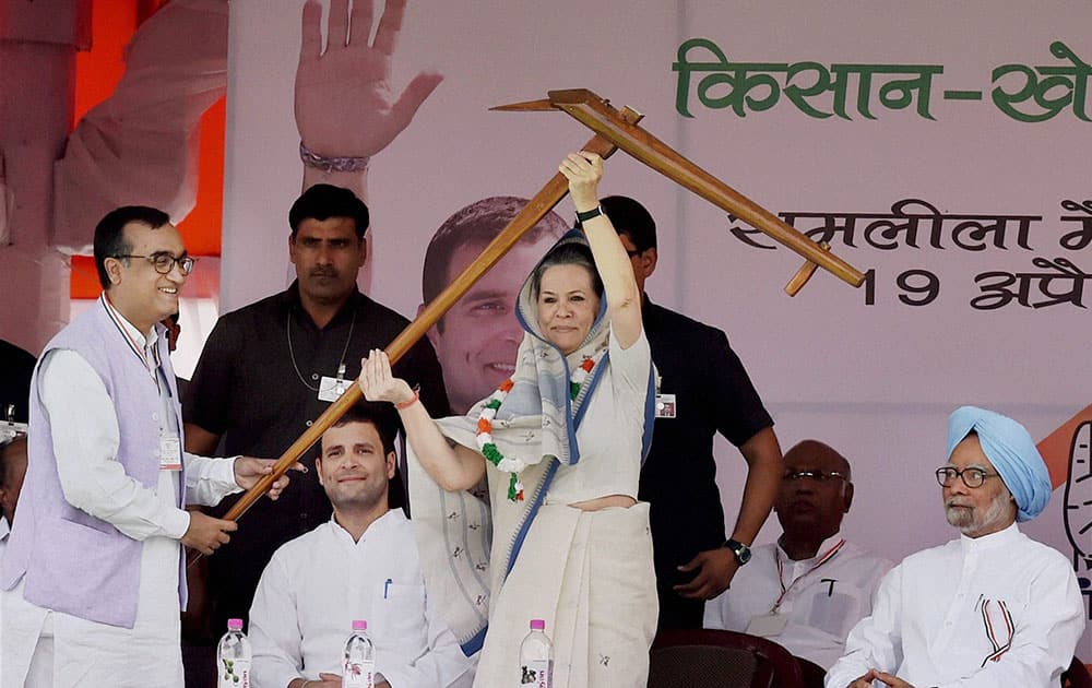 Congress President Sonia Gandhi being handed over a large wooden plough by party leader Ajay Maken (L) during the farmers rally at Ramlila Maidan in New Delhi.