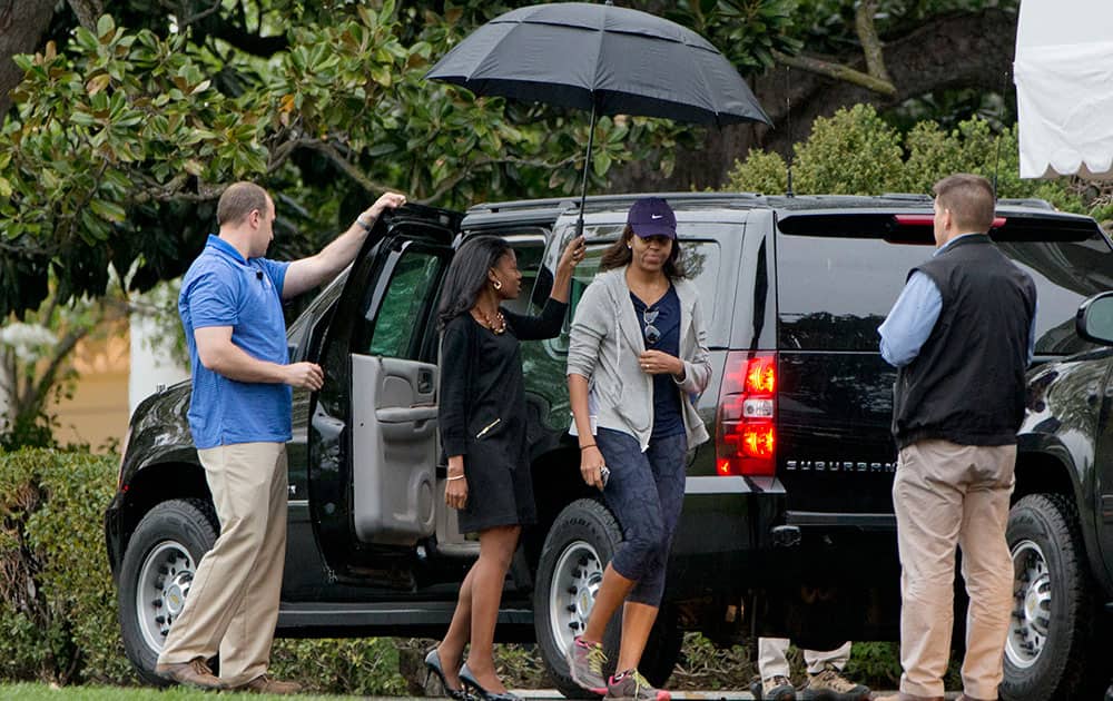 First lady Michelle Obama walks under an umbrella on return to the White House in Washington after hiking with President Barack Obama and their daughters at Great Falls Park in Great Falls, Va.